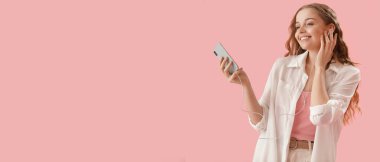 Akıllı telefonlu mutlu genç bir kadın pembe arka planda müzik dinliyor ve mesaj için yeri var.