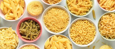 Açık arkaplan ve üst görünümde farklı tipte makarna içeren kaseler