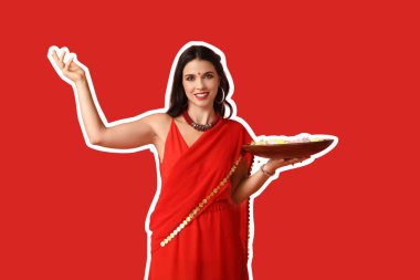 Kırmızı arka planda mumları ve çiçekleri olan güzel bir Hintli kadın. Divaly kutlaması