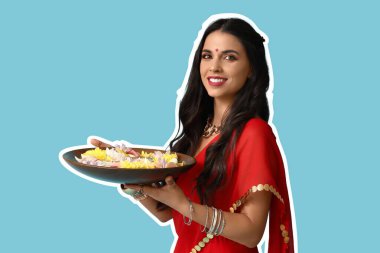 Elinde mumlar ve açık mavi arka planda çiçekler olan güzel bir Hintli kadın. Divaly kutlaması