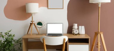 Renkli duvarın yanında modern dizüstü bilgisayarı olan işyeri