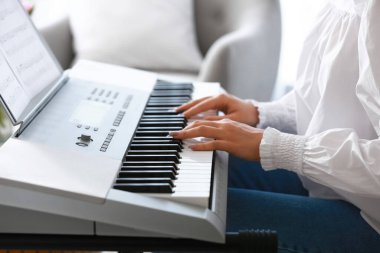 Evde sentezleyici çalan genç bayan müzisyen, yakın plan.