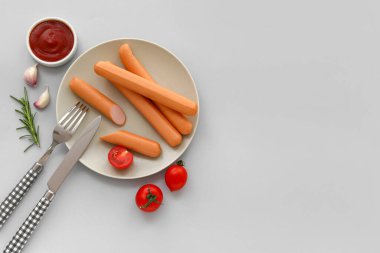 Domatesli lezzetli sosisler ve gri arka planda ketçap.