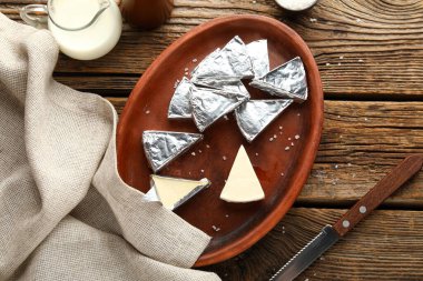 Ahşap zemin üzerinde lezzetli işlenmiş peynir üçgenleriyle dolu bir tabak.