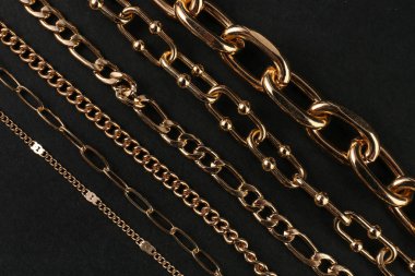 Güzel zincir bilezikler ve siyah arka planda kolyeler.