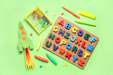 Abaküslü kağıt roket, ahşap harfler ve yeşil arka planda kırtasiye.