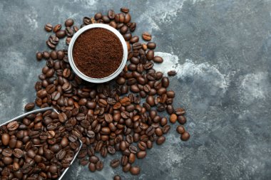 Kahve tozu ve arkaplanda fasulye olan bir kase.