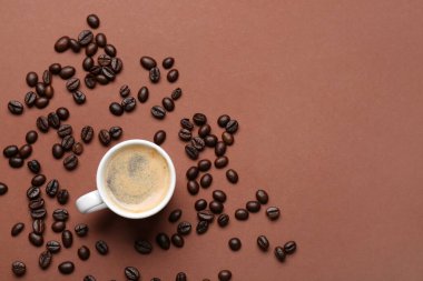 Kahverengi arka planda bir fincan sıcak espresso ve kahve çekirdeği.