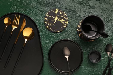 Yeşil grunge masasında temiz tabak, fincan ve altın çatal bıçak takımı.