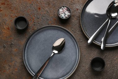 Kahverengi grunge masasında temiz tabaklar, tuz ve kaşıklar.