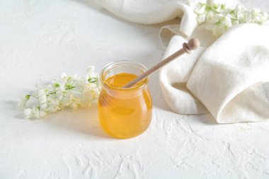 Akasya çiçekli bal kavanozu ve açık arkaplanda dipper.