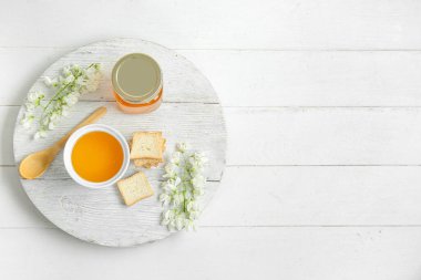 Tatlı ballı kompozisyon, akasya çiçekleri ve hafif ahşap arka planda krakerler