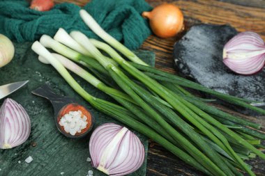 Kahverengi ahşap zemin üzerinde farklı soğan ve baharatlar içeren tahtalar.