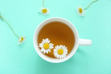 Turkuaz arka planda çiçekli bir fincan sıcak çay