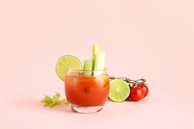 Pembe arka planda kereviz ve limonlu bir bardak Bloody Mary.