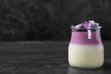 Bir bardak yaban mersinli panna cotta ve siyah masada güzel ortanca çiçekleri.