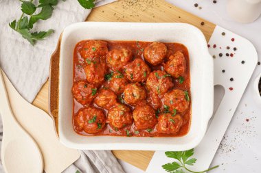 Domates soslu lezzetli köfteler ve beyaz arka planda maydanoz pişirmek.