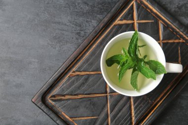 Ahşap tahta üzerinde bir fincan taze nane çayı ile grunge siyah arka planda