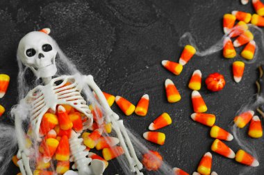 Tatlı Cadılar Bayramı şekerlemeleri ve koyu arka planda iskelet, yakın plan.