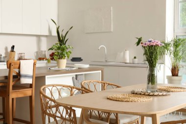 Mutfaktaki yemek masasında çiçekli vazo.