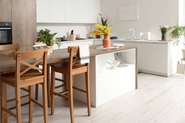 Beyaz tezgahlı ve ada masalı modern mutfağın içi.