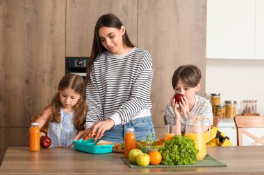 Anne küçük çocukları için mutfakta öğle yemeği hazırlıyor.