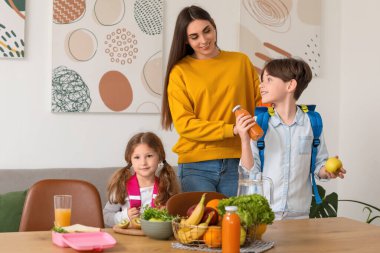 Anne küçük çocukları için mutfakta öğle yemeği hazırlıyor.