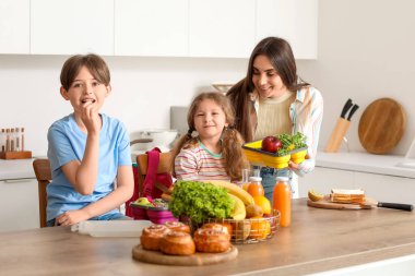 Anne küçük çocukları için mutfakta öğle yemeği hazırlıyor.