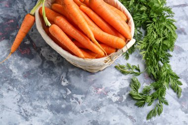 Mavi arka planda taze havuç dolu sepet.