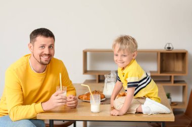Babasıyla birlikte oturma odasında süt içen küçük bir çocuk.
