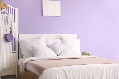 Rahat yataklı, beyaz yastıklı ve katlanmış perdeli şık bir yatak odası.