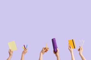 Hands with school supplies on lilac background