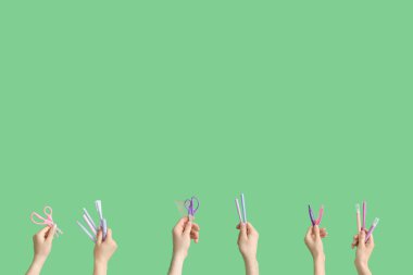 Hands with school accessories on green background