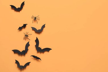 Turuncu arka planda Cadılar Bayramı partisi için kağıt yarasalar ve örümcekler.