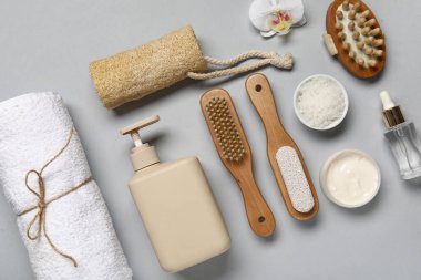 Gri arka planda farklı banyo malzemeleri ve kozmetik ürünleri içeren kompozisyon