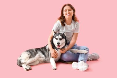 Pembe arka planda köpekli mutlu genç bir kadın.