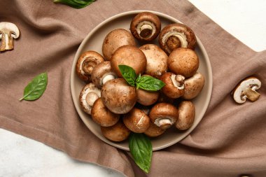 Taze mantarlı tabak ve beyaz arka planda fesleğen.