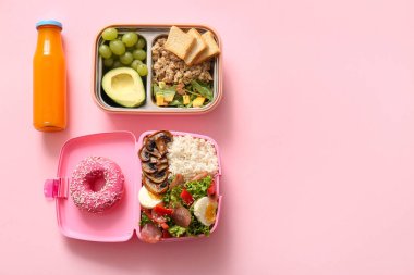 Farklı lezzetli yemekleri olan beslenme çantaları ve pembe arka planda bir şişe meyve suyu.