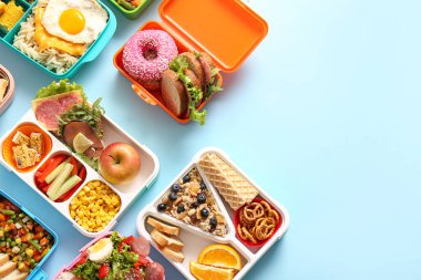 Mavi arka planda farklı lezzetli yemekleri olan bir sürü beslenme çantası.