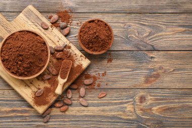 Kakao tozlu kaseler ve ahşap arka planda fasulyeler.