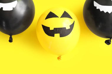 Sarı arka planda farklı komik Cadılar Bayramı balonları
