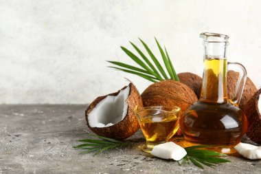 Duvarın yanındaki grunge grisi masada hindistan cevizi kozmetik yağı var.