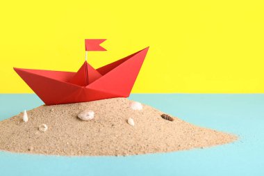 Kum ve deniz kabuklarının renginde kırmızı origami teknesi