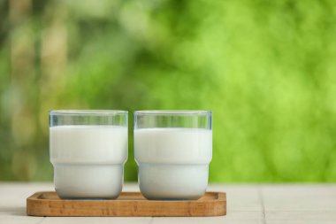 Tahta tahta tahta tahta, beyaz fayans masasında taze süt bardakları.