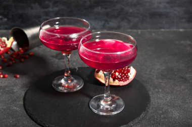 Siyah zemin üzerinde Cosmopolitan kokteyli ve nar olan tahta