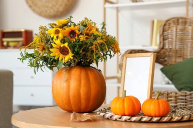 Sonbahar çiçekleri ve çerçeveli balkabakları oturma odasındaki masada.