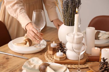 Yemek odasında kurumuş çiçeklerle masa hazırlayan bir kadın.