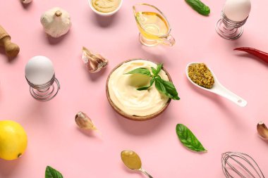 Bir kase taze mayonez ve pembe arka planda malzemeler.