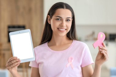 Evde kurabiye ve tablet bilgisayarlı genç bir kadın var. Göğüs kanseri farkındalığı konsepti