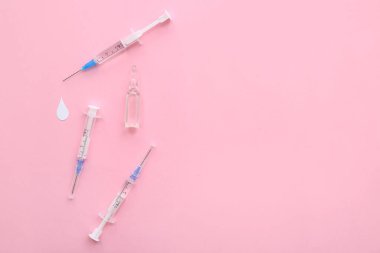 Pembe arka planda ampul bulunan tıbbi şırıngalar.